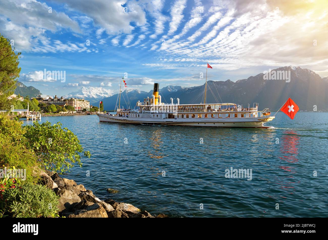 Beautiful summer evening landscape of Lake Geneva with picturesque shores and pleasure ship against Alpine mountains in Montreux, Switzerland Stock Photo