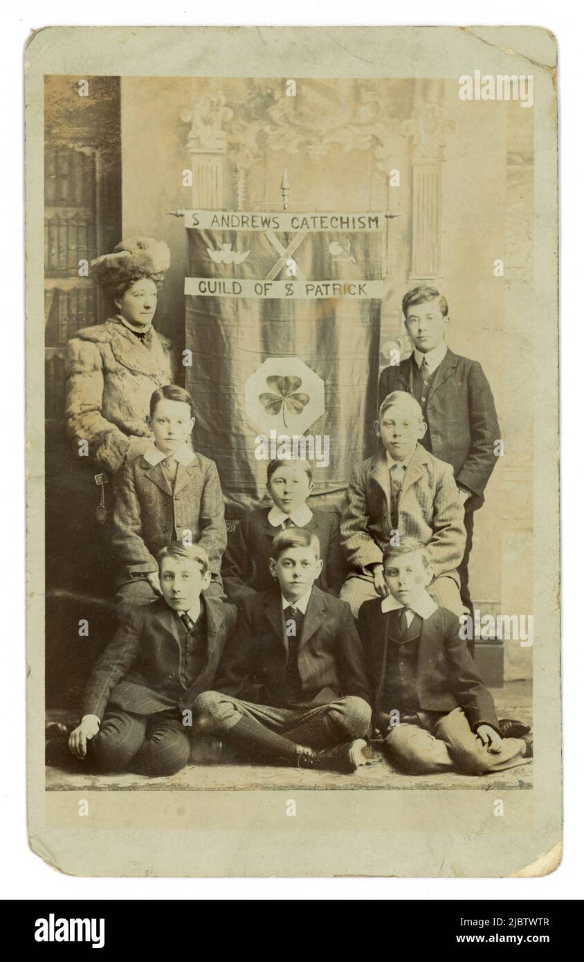 Original Edwardian boys at a catechism class, Sunday School maybe. The woman in furs is possibly Lady Loder, the landed gentry school benefactor.. St. Andrew's Catechism, Guild of St. Patrick is written on the banner. St. Andrew's school written on reverse,  Worthing, West Sussex, U.K. circa 1905 Stock Photo