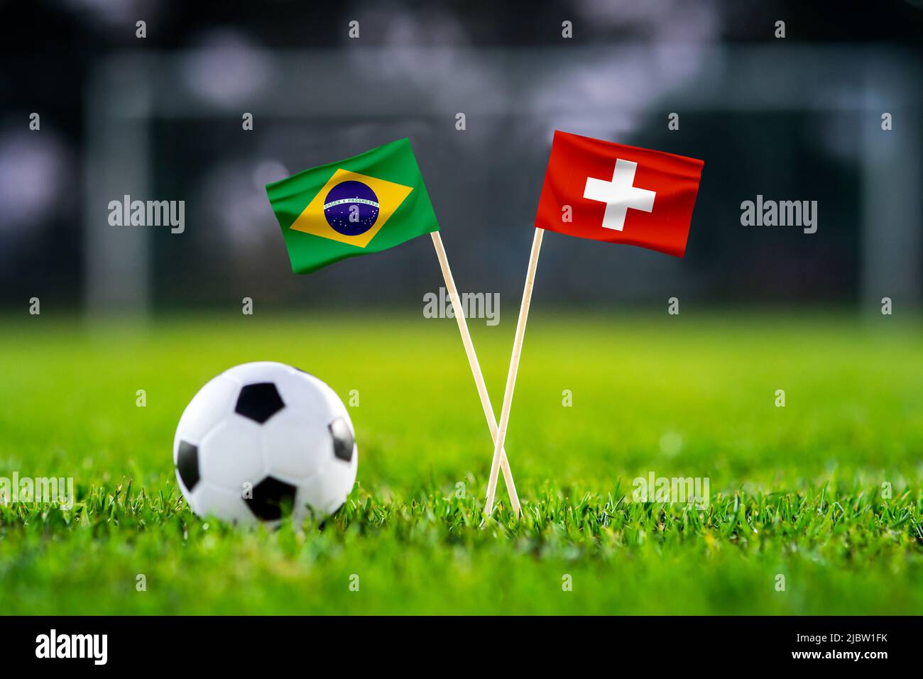 Brazil vs. Switzerland, Stadium 974, Football match wallpaper, Handmade national flags and soccer ball on green grass. Football stadium in background. Stock Photo