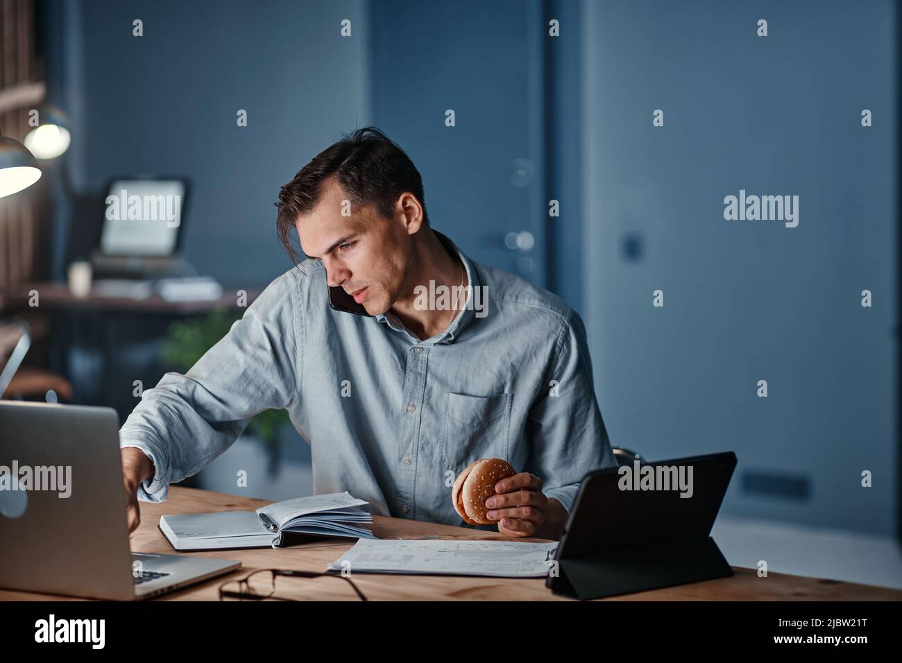 young businessman talking on a smartphone and using a digital tablet. Stock Photo