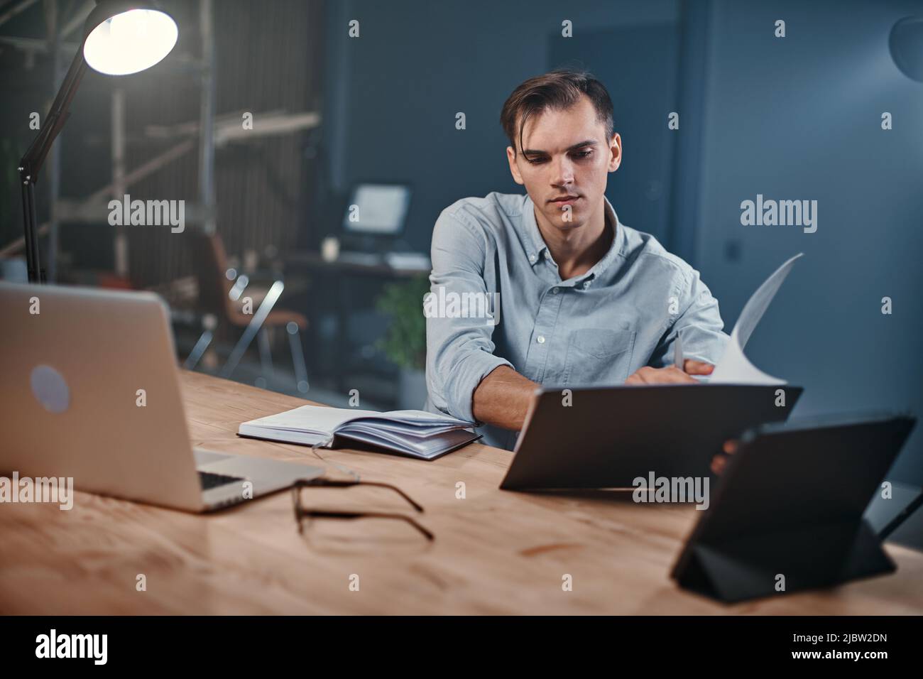 young businessman taking notes in a notebook in a night office. Stock Photo