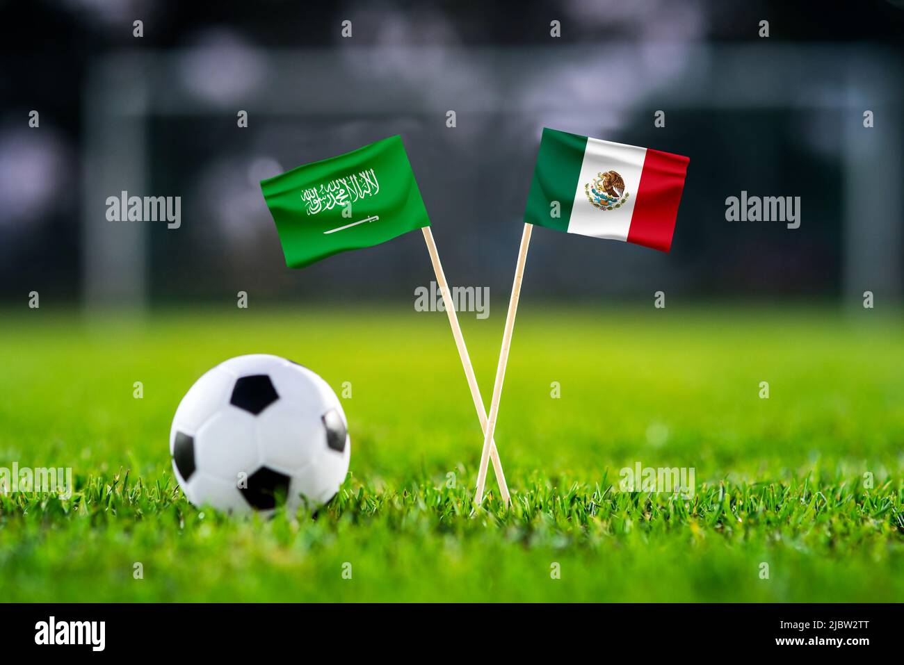 Saudi Arabia vs. Mexico, Lusail, Football match wallpaper, Handmade national flags and soccer ball on green grass. Football stadium in background. Bla Stock Photo
