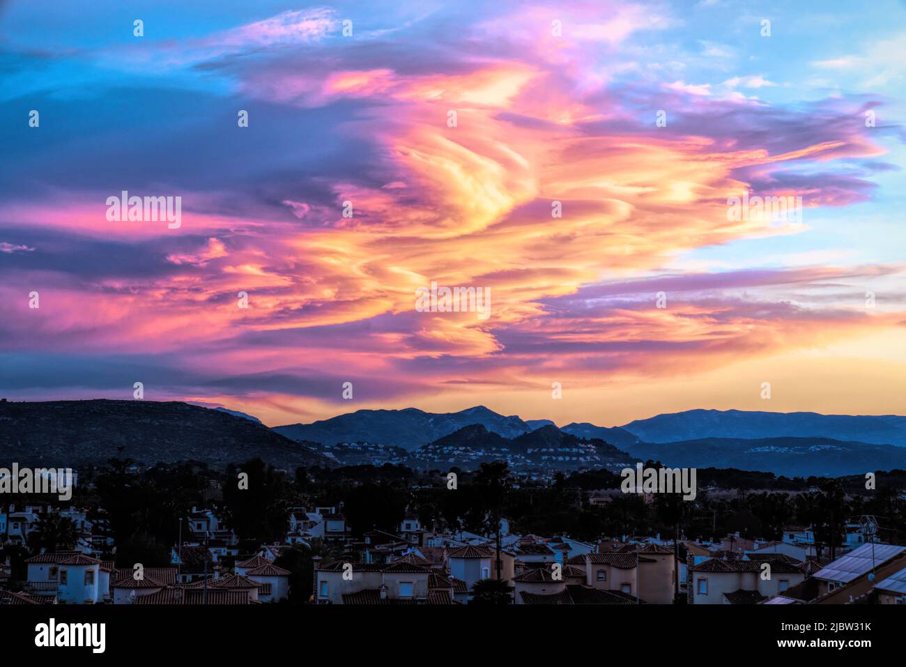 Denia Spain sunset with amazing bright colourful clouds over the mountains Stock Photo
