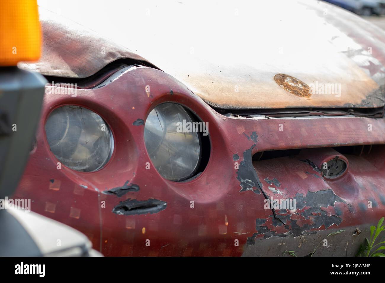 Broken headlights as a result of a collision. Broken red car after an