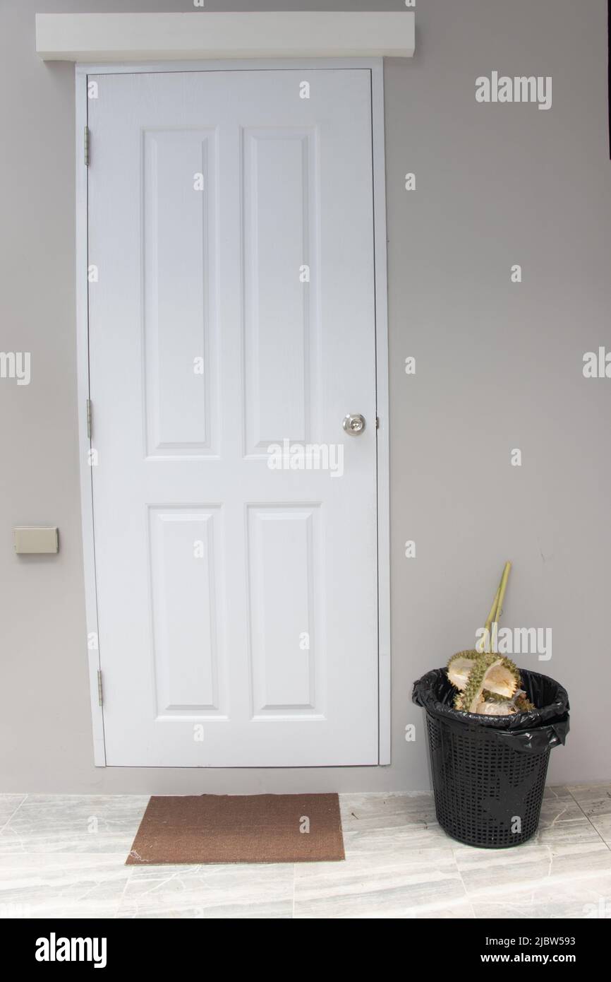 Trash can with remnants of durian behind closed doors on a porch Stock Photo