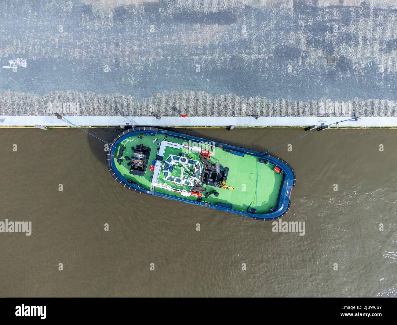 Green tugboat docked on the river Scheldt in Antwerp. Drone aerial top down view from above Stock Photo