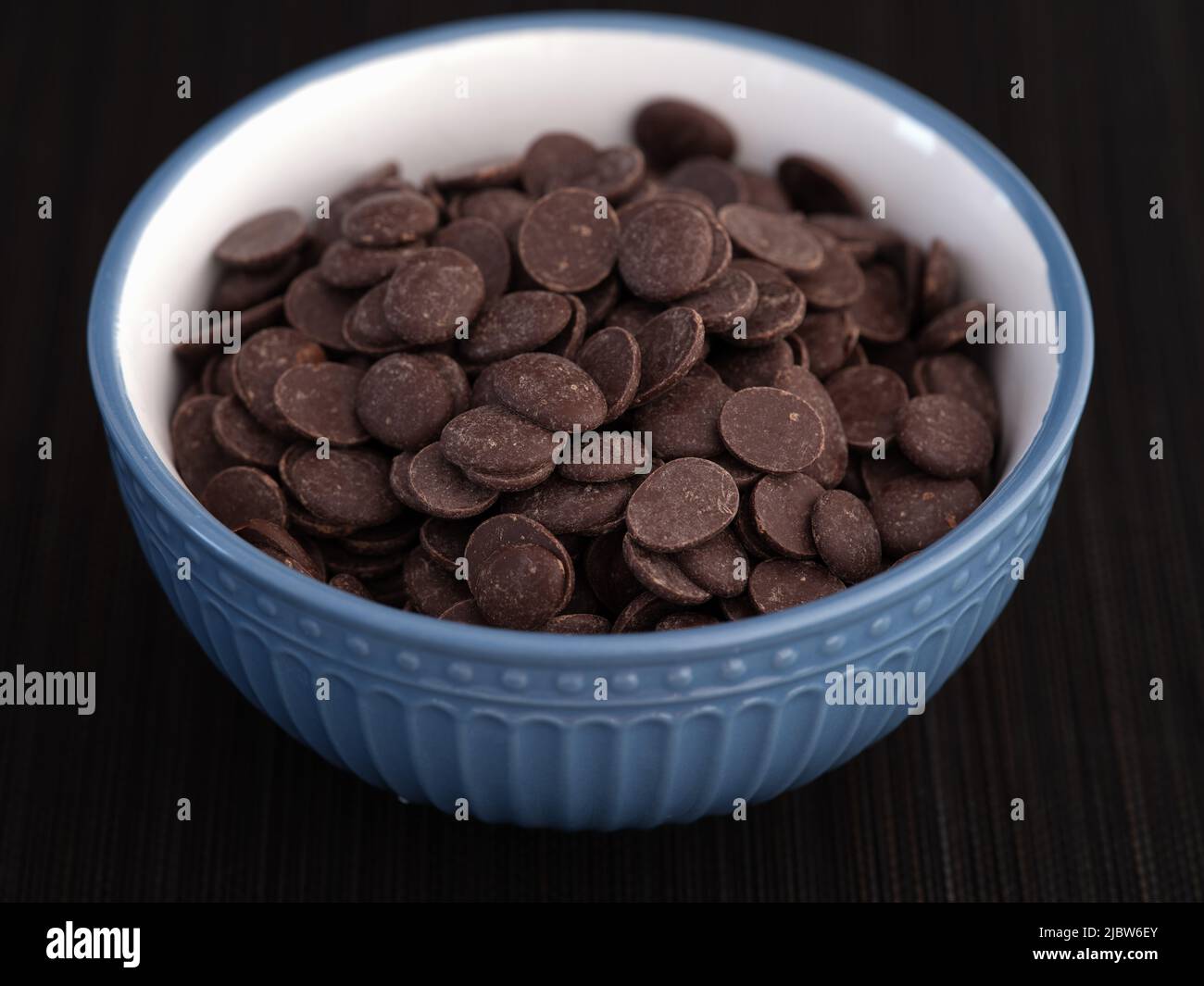 A pile of chocolate chips in a bowl. Low key. Close up. Stock Photo