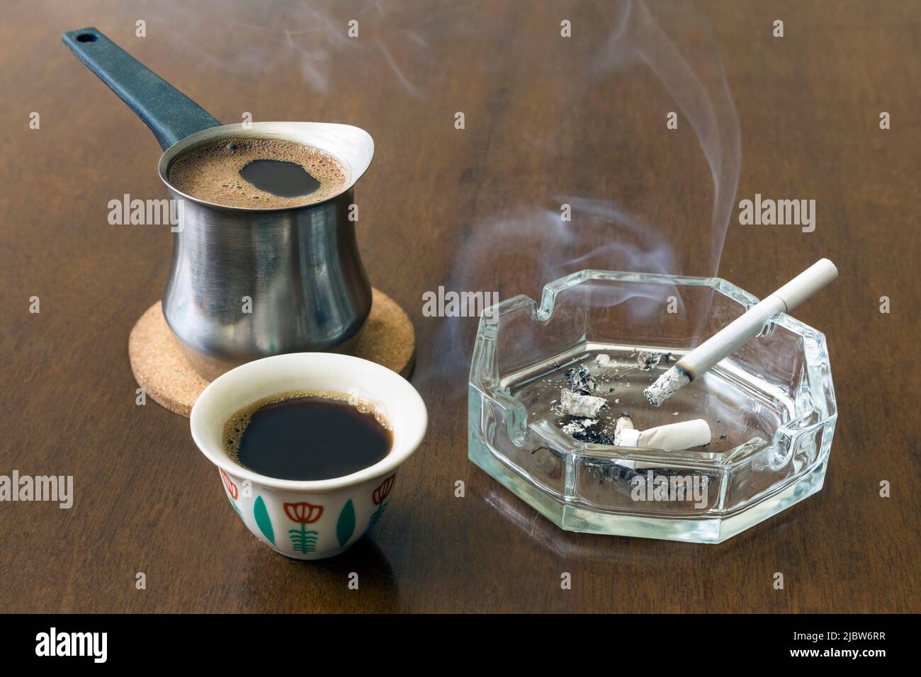 Traditional Lebanese coffee pot and cup with ashtray and cigarette on a wooden table Stock Photo