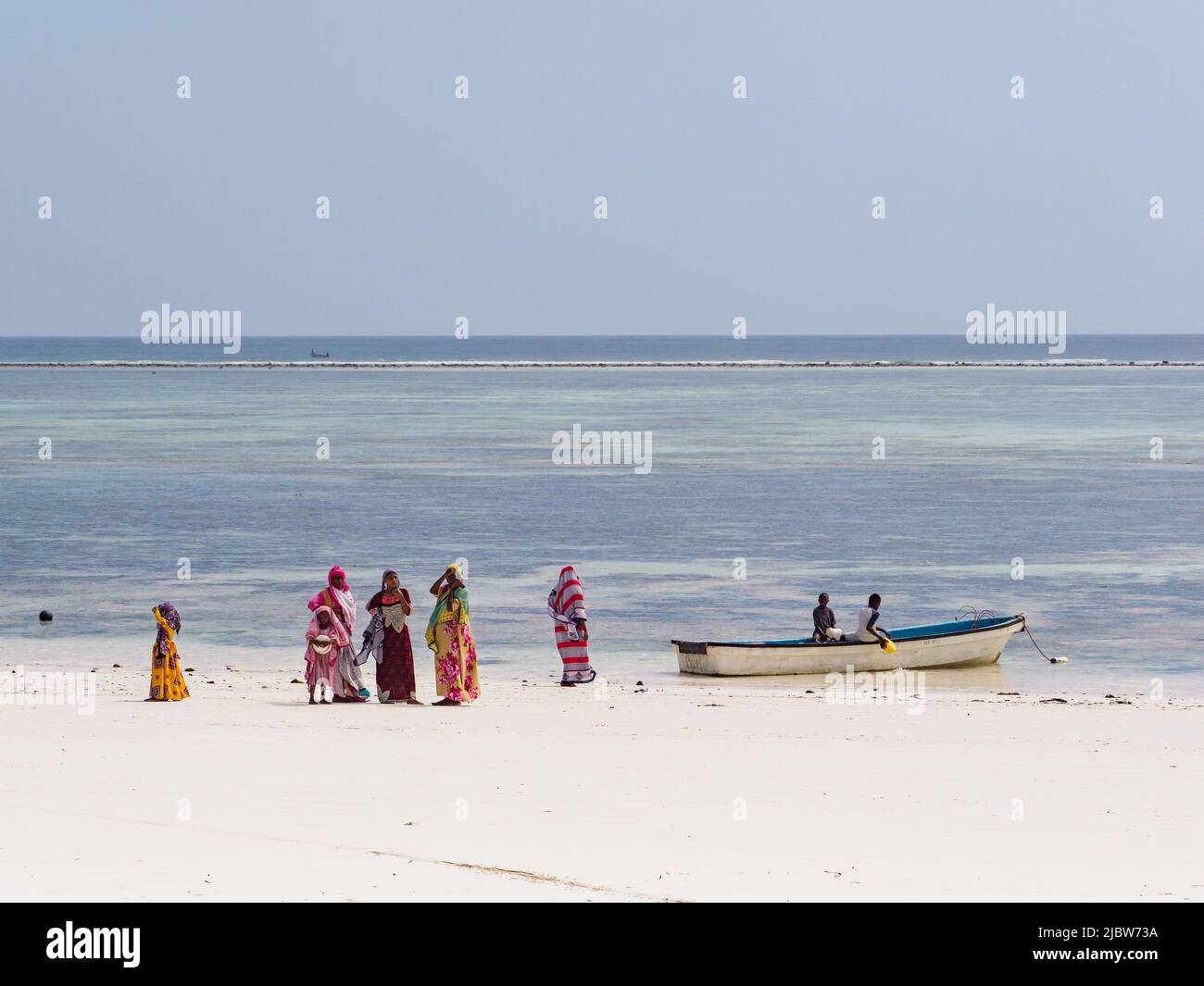 Matemwe, Zanzibar - Jan, 2021: Women in colorful clothes and headscarves. The daily life of the local people on the sandy beach of Zanzibar. Tanzania, Stock Photo