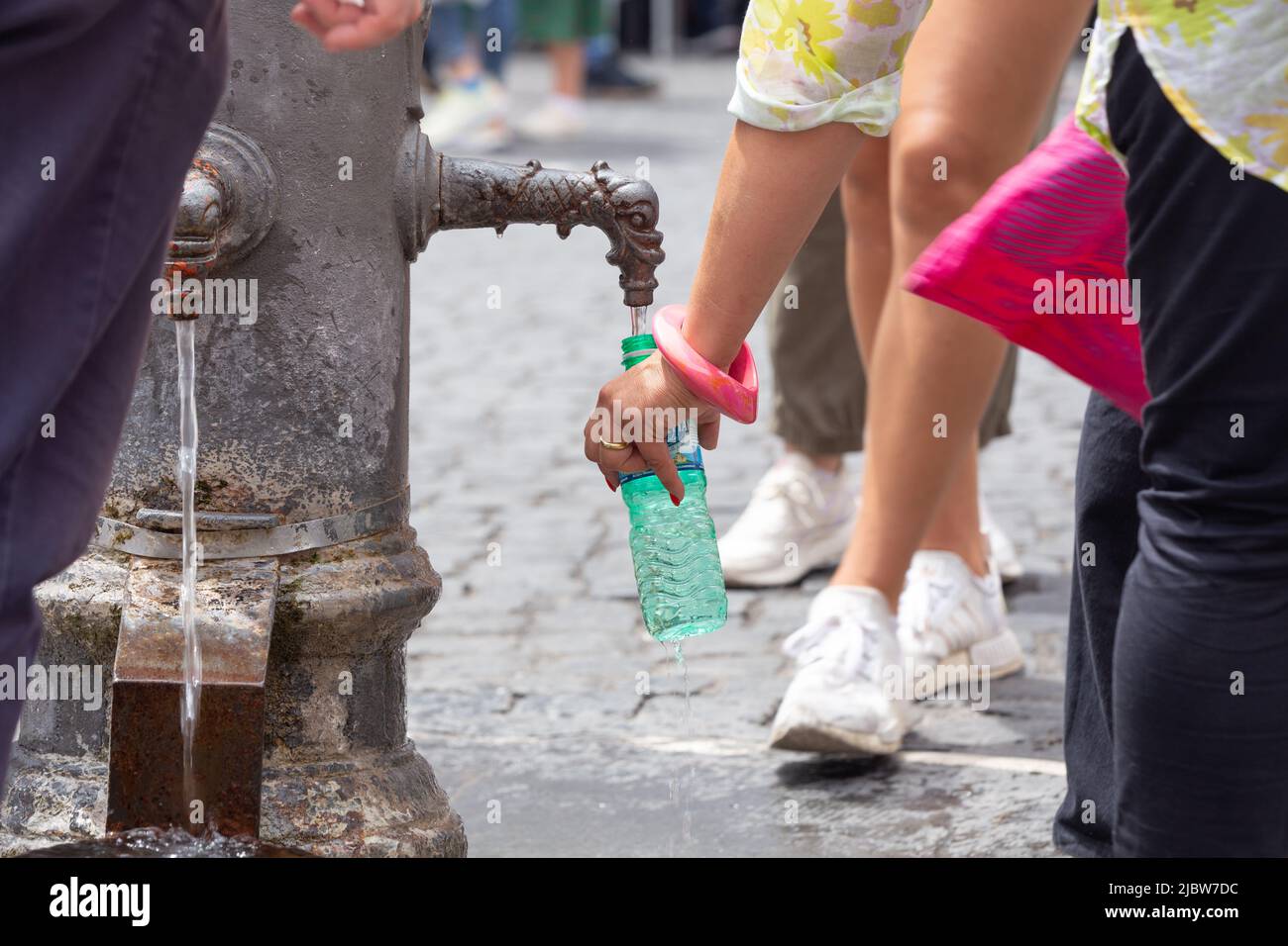 Tourists fill water bottles at a drinking fountain in front of Pantheon