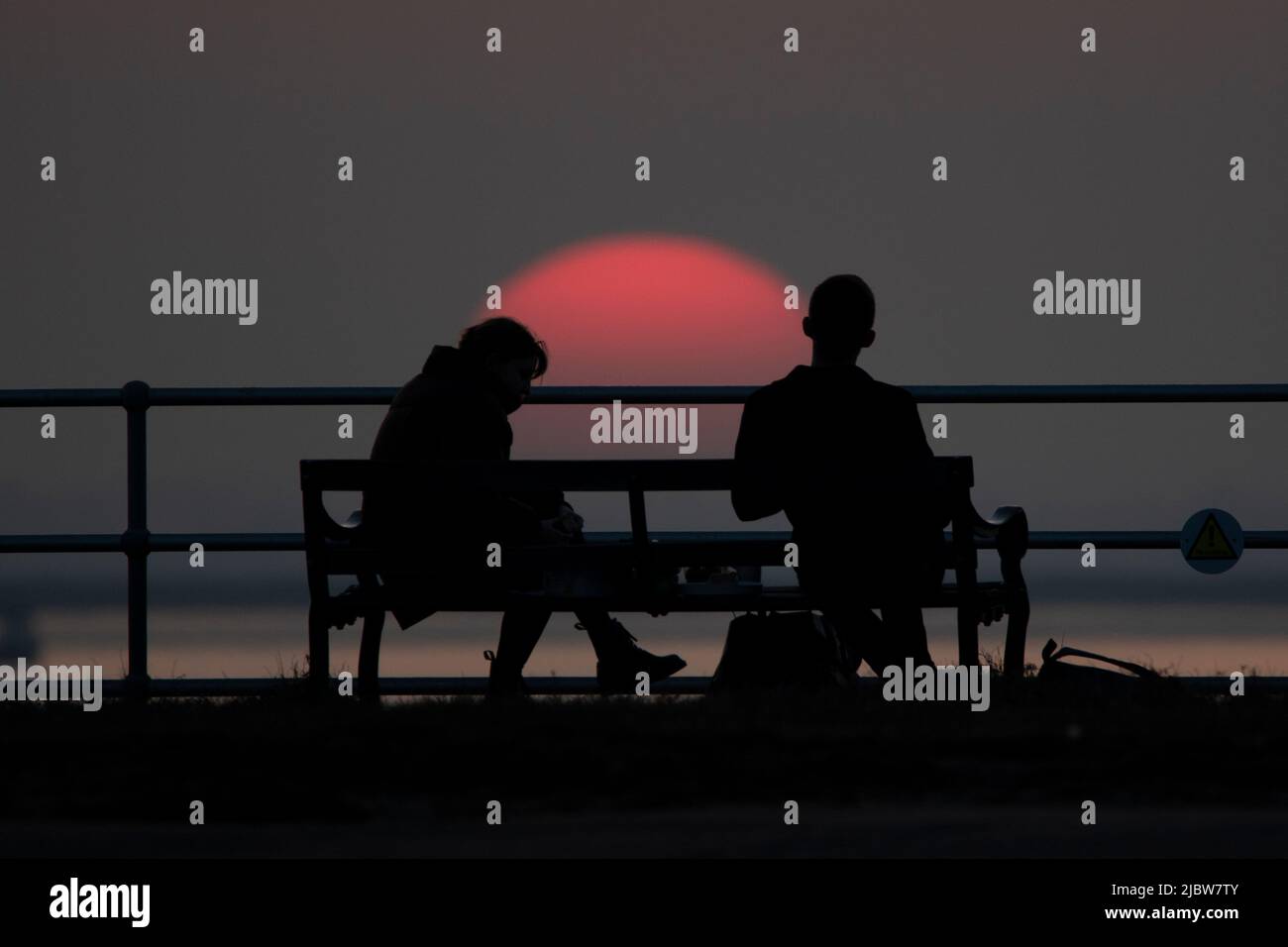 A couple on their third date watch the setting sun while having a bite to eat. Stock Photo