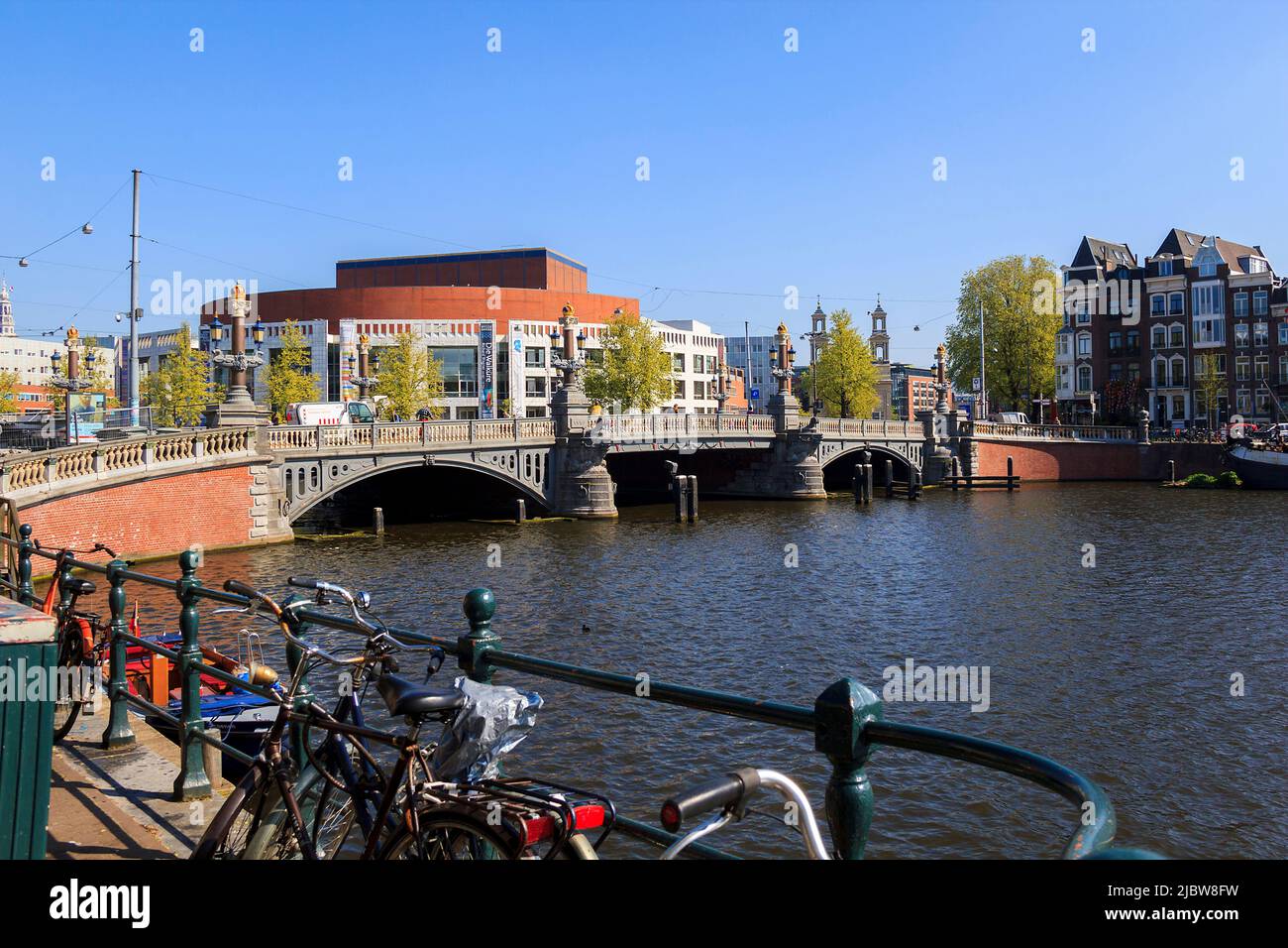 There are The Opera House and the Blue Bridge through river Amstel May 5, 2013 in Amsterdam, Netherlands. Stock Photo