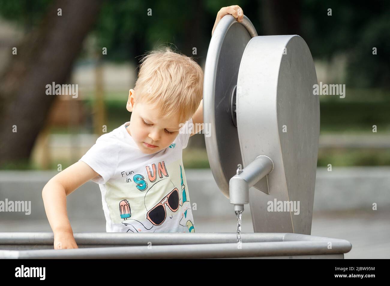 Little boy playing with water tap outdoors. Stock Photo