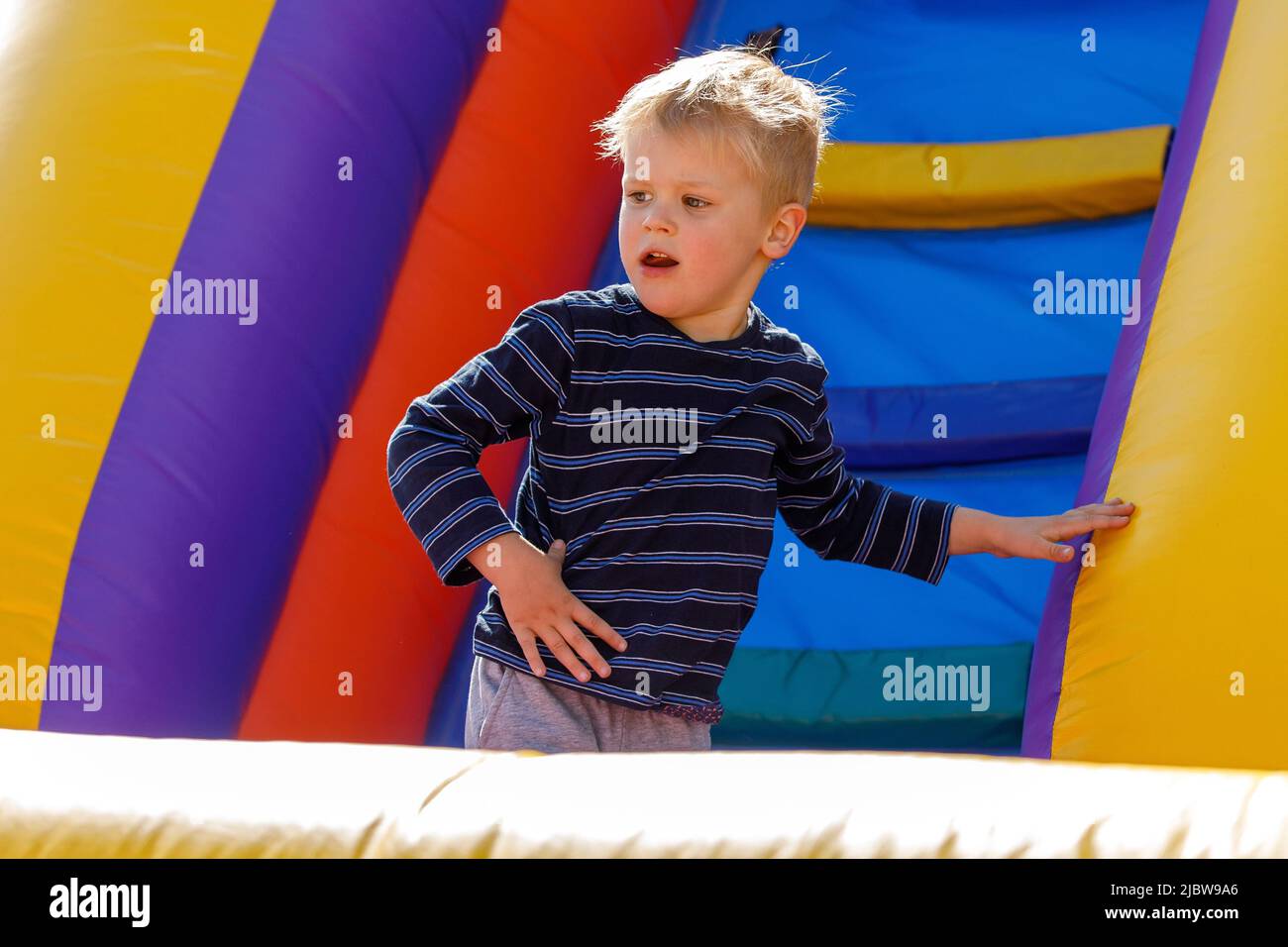 Child jumping on colorful playground trampoline. Kid jump in inflatable bounce castle on kindergarten birthday party. Activity and play center for you Stock Photo
