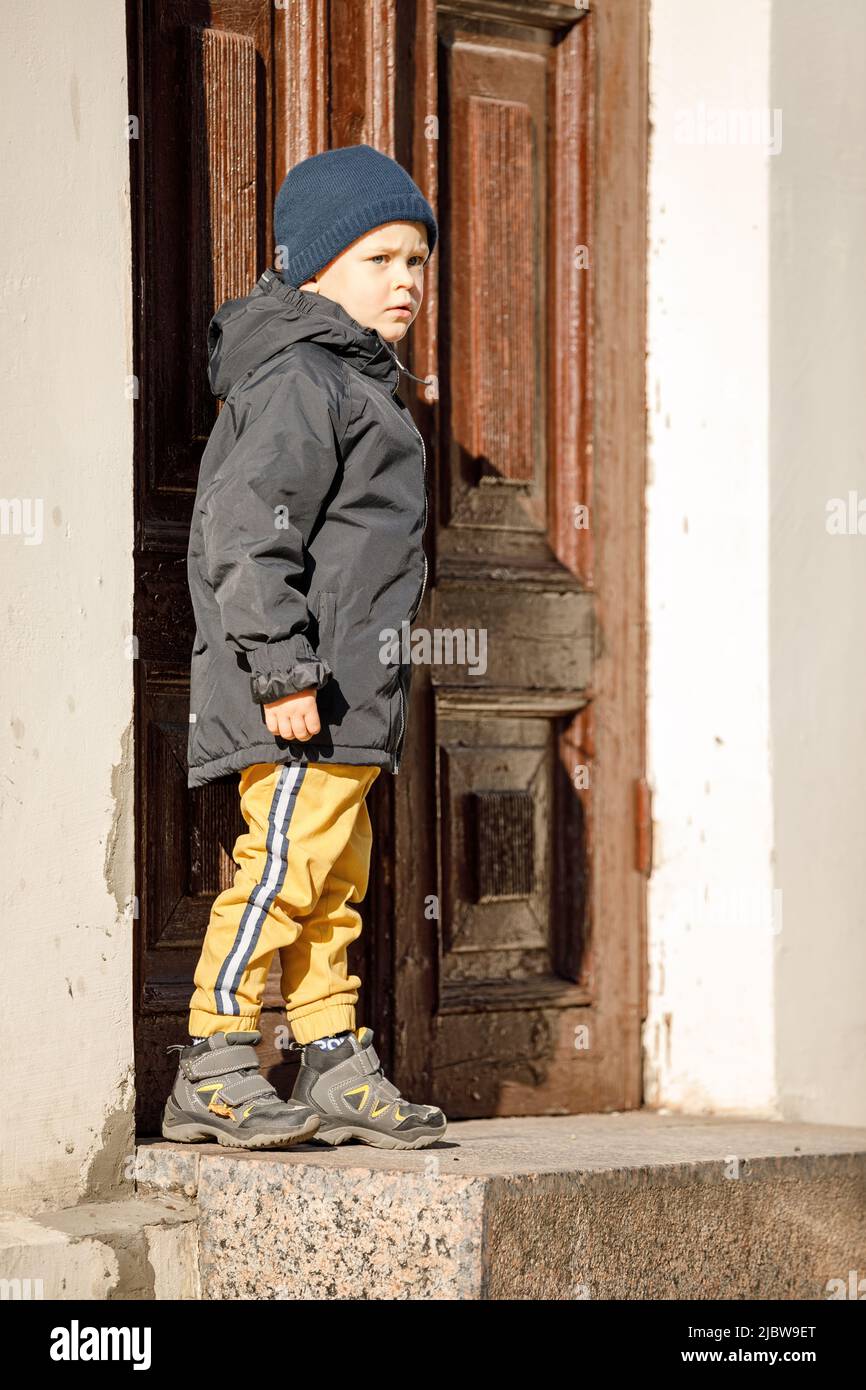 A cute boy on an autumn day at the ancient door in the center of Klaipeda Old Town. Stock Photo