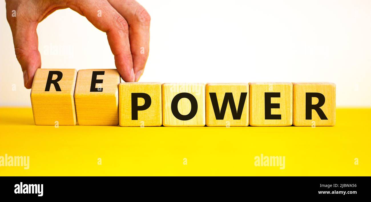 Power or repower symbol. Businessman turns wooden cubes and changes concept words Power to Repower. Beautiful yellow table white background. Business Stock Photo