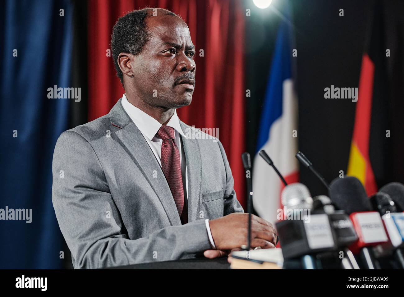 Serious American politician in formal suit standing at platform with microphones and giving an interview for television Stock Photo