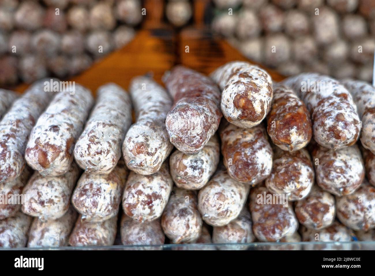 Stacks of dry-cured sausages - saucisson, typically made of pork, or a mixture of pork and other meats. Stock Photo