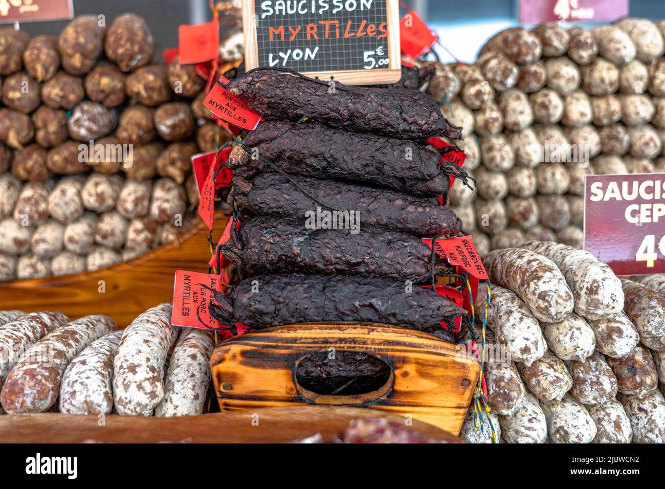 Stacks of dry-cured sausages - saucisson, typically made of pork, or a mixture of pork and other meats. Stock Photo