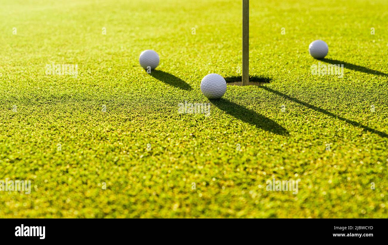 Three golf balls on the green grass near hole on a golf course at sunset  Stock Photo - Alamy