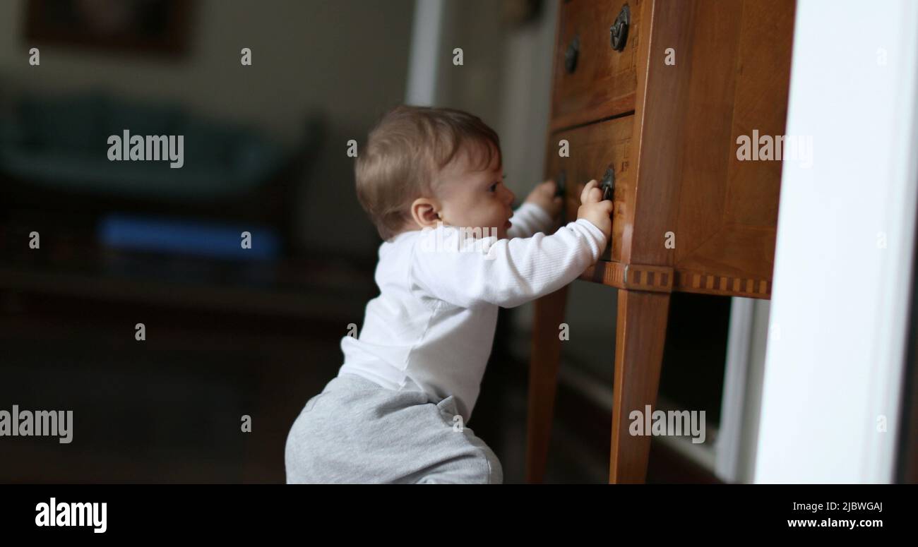 Baby learning to stand by holding into home furniture. Infant toddler