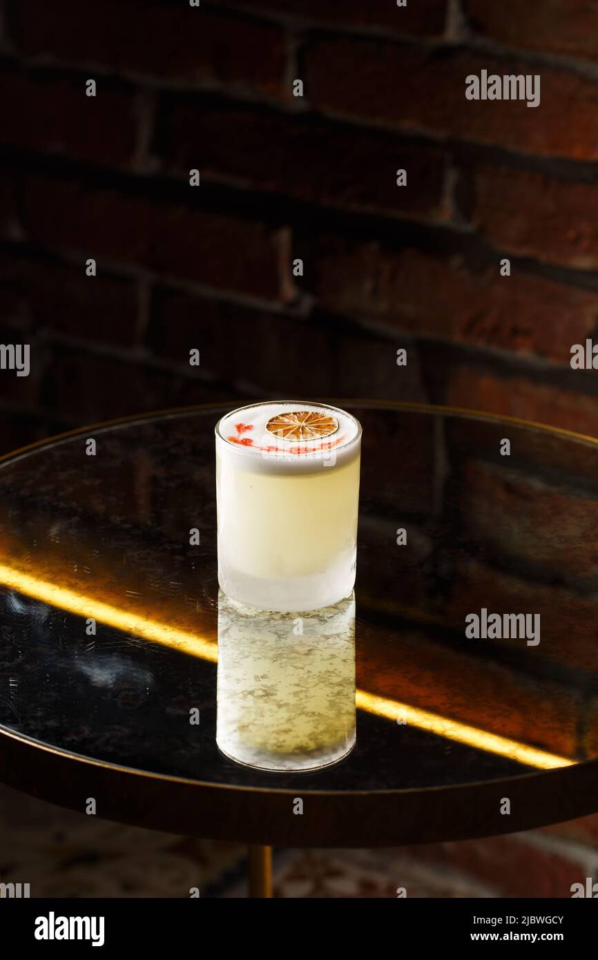 Pisco sour cocktail whiskey with lime, egg white, sugar syrup in glass on dark background
