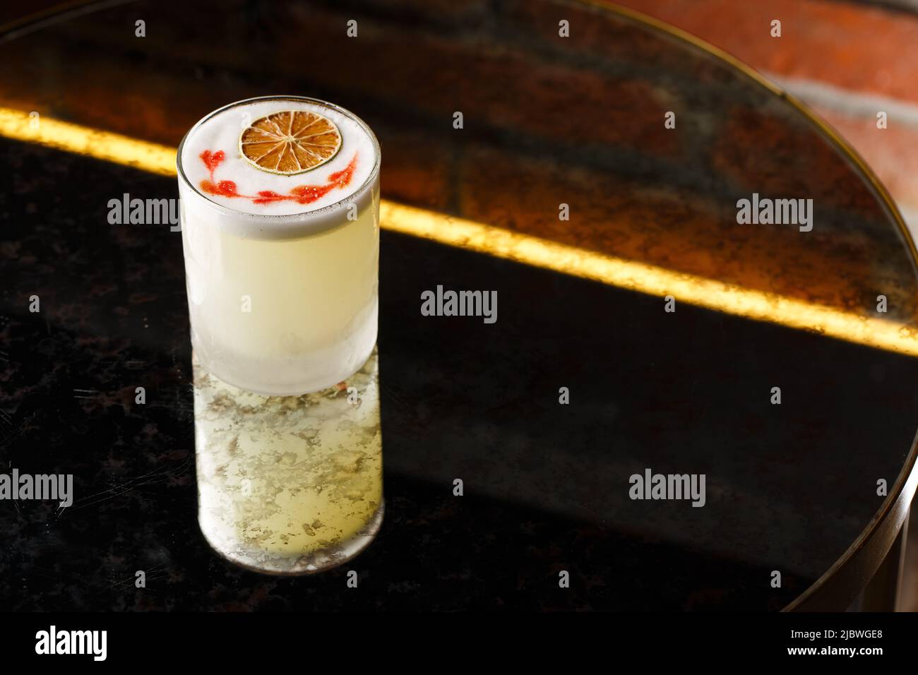 Pisco sour cocktail whiskey with lime, egg white, sugar syrup in glass on dark background