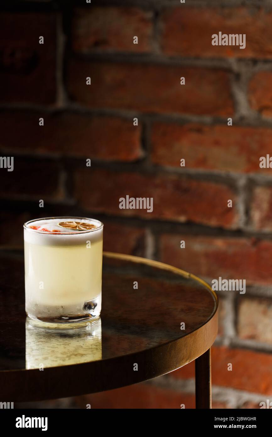 Pisco sour cocktail whiskey with lime, egg white, sugar syrup in glass on dark background