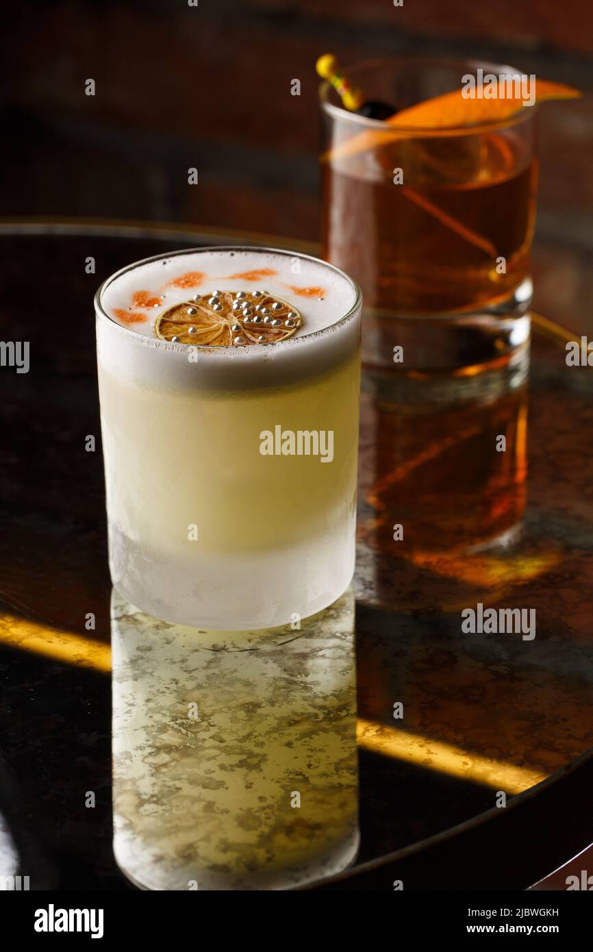 Pisco sour cocktail whiskey with lime, egg white, sugar syrup in glass on dark background