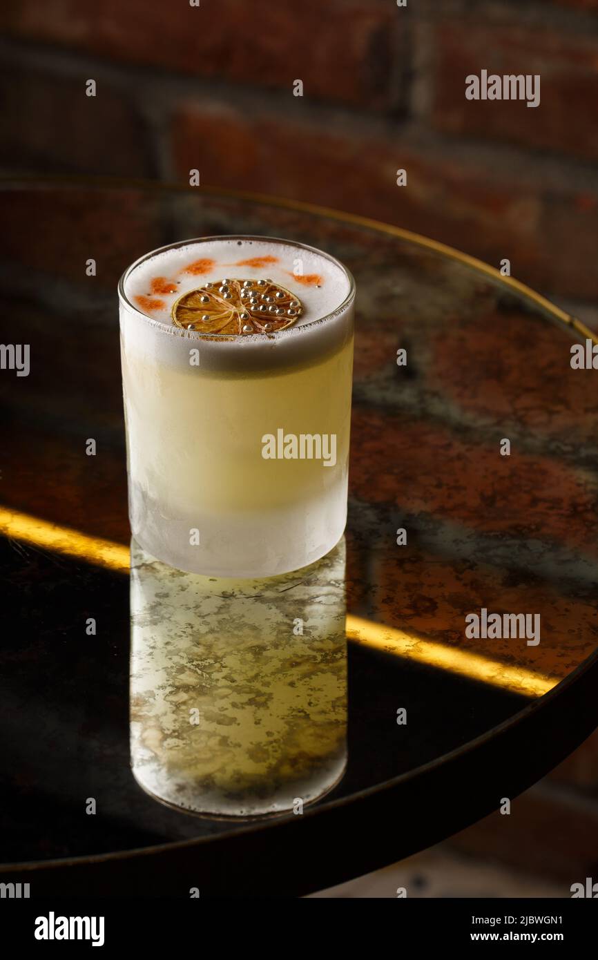 Pisco sour cocktail whiskey with lime, egg white, sugar syrup in glass on dark background