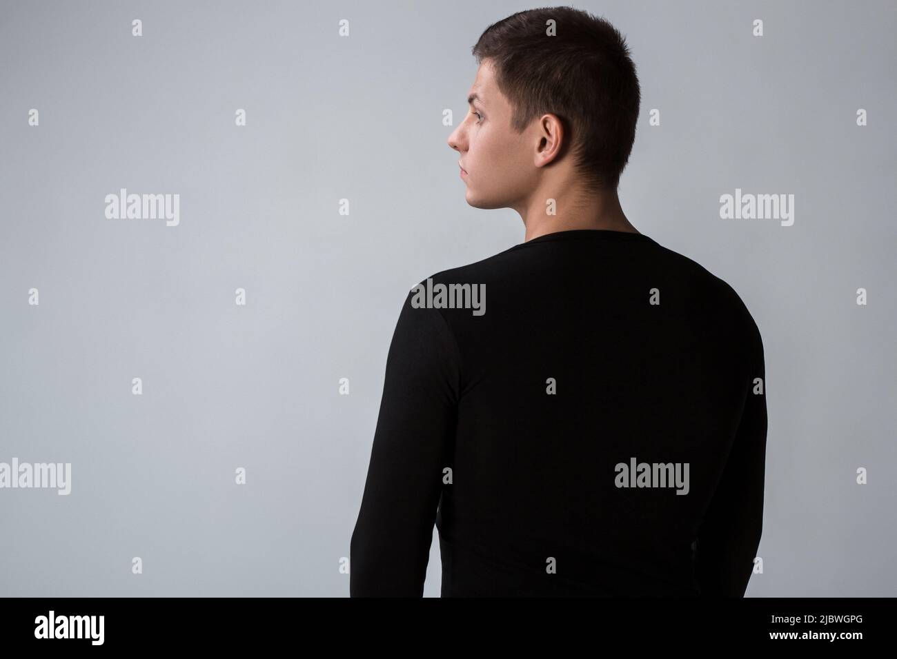 Back view of man in black sweater. Standing young guy. Rear view Stock