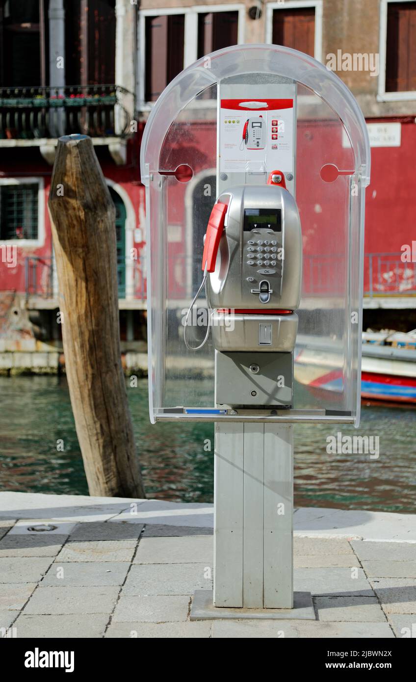 Venice, VE, Italy - May 18, 2020: old italian phone box and the navigable canal on background Stock Photo