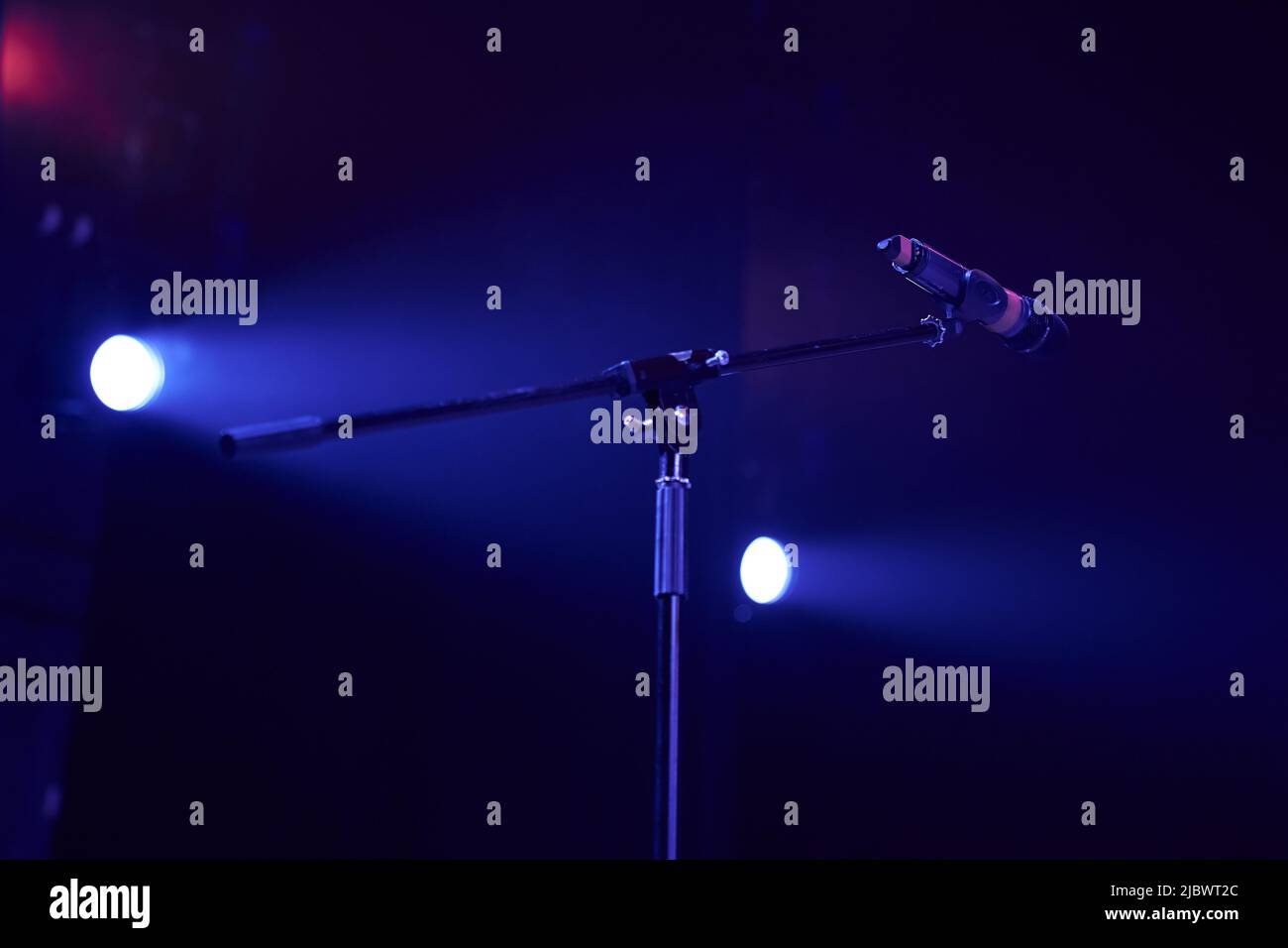 Professional stage microphone in a bright spotlight on a dark