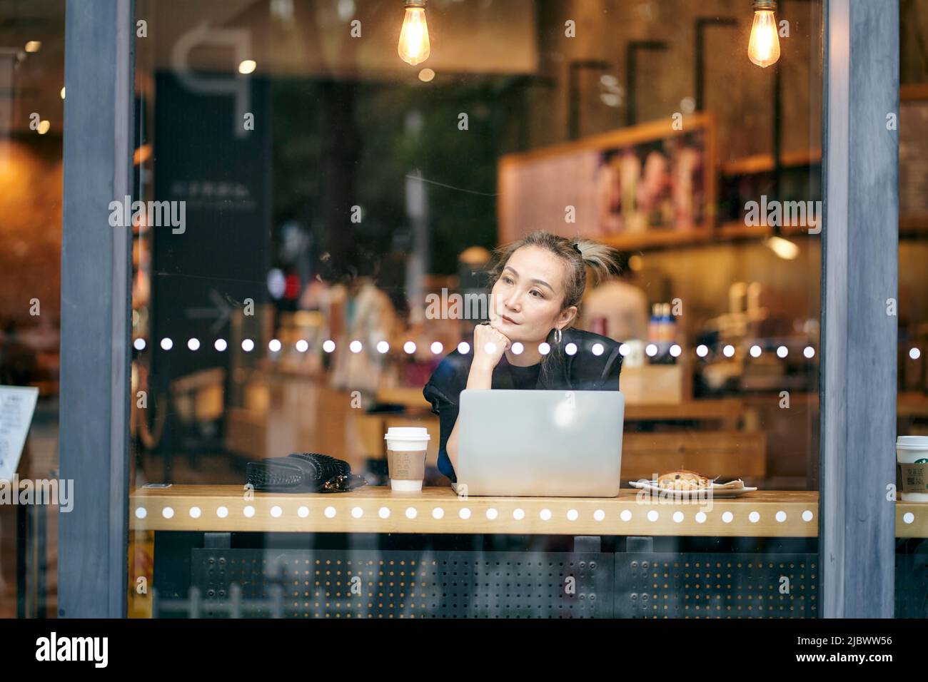 asian woman working in coffee shop using laptop computer Stock Photo