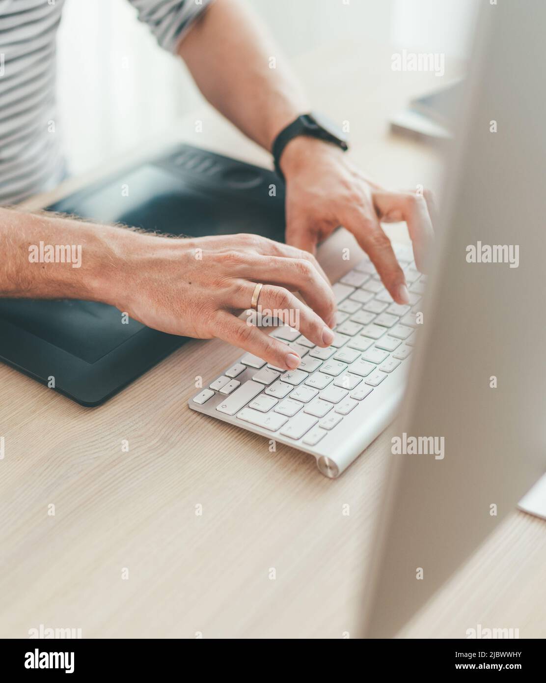 Writer typing modern computer keyboard writing novel sitting at the white wood table. Distance or freelance work on worldwide quarantine time concept Stock Photo