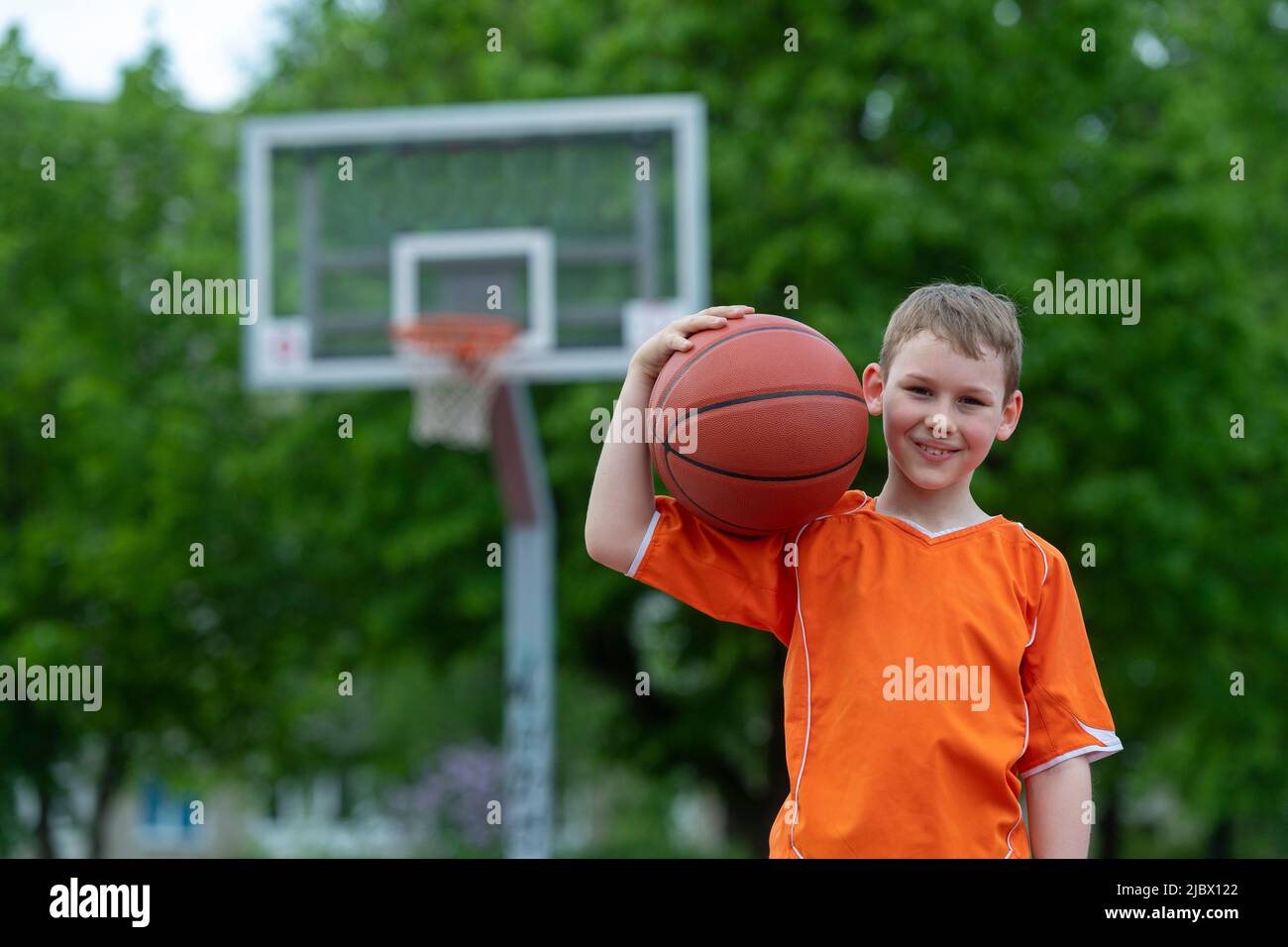 Boy playing basketball on a park court. Concept of a sports lifestyle, training, camp, leisure, vacation. Horizontal sport theme poster, greeting card Stock Photo