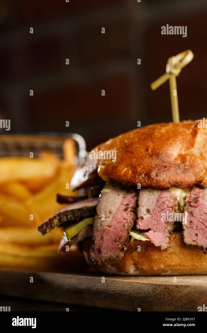 Pastrami sandwich on rye bread served with pickles and mustard sauce