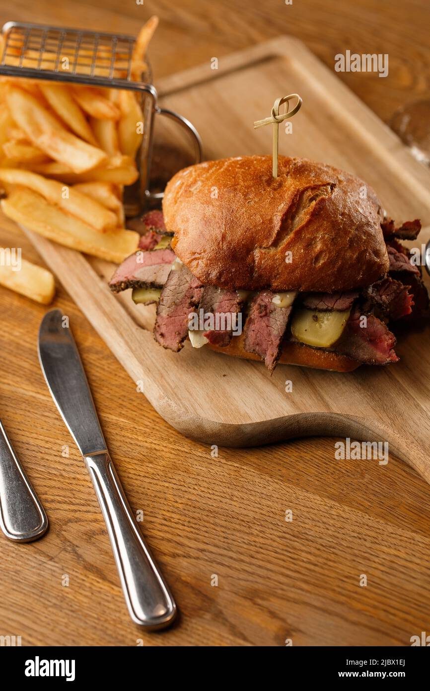 Pastrami sandwich on rye bread served with pickles and mustard sauce