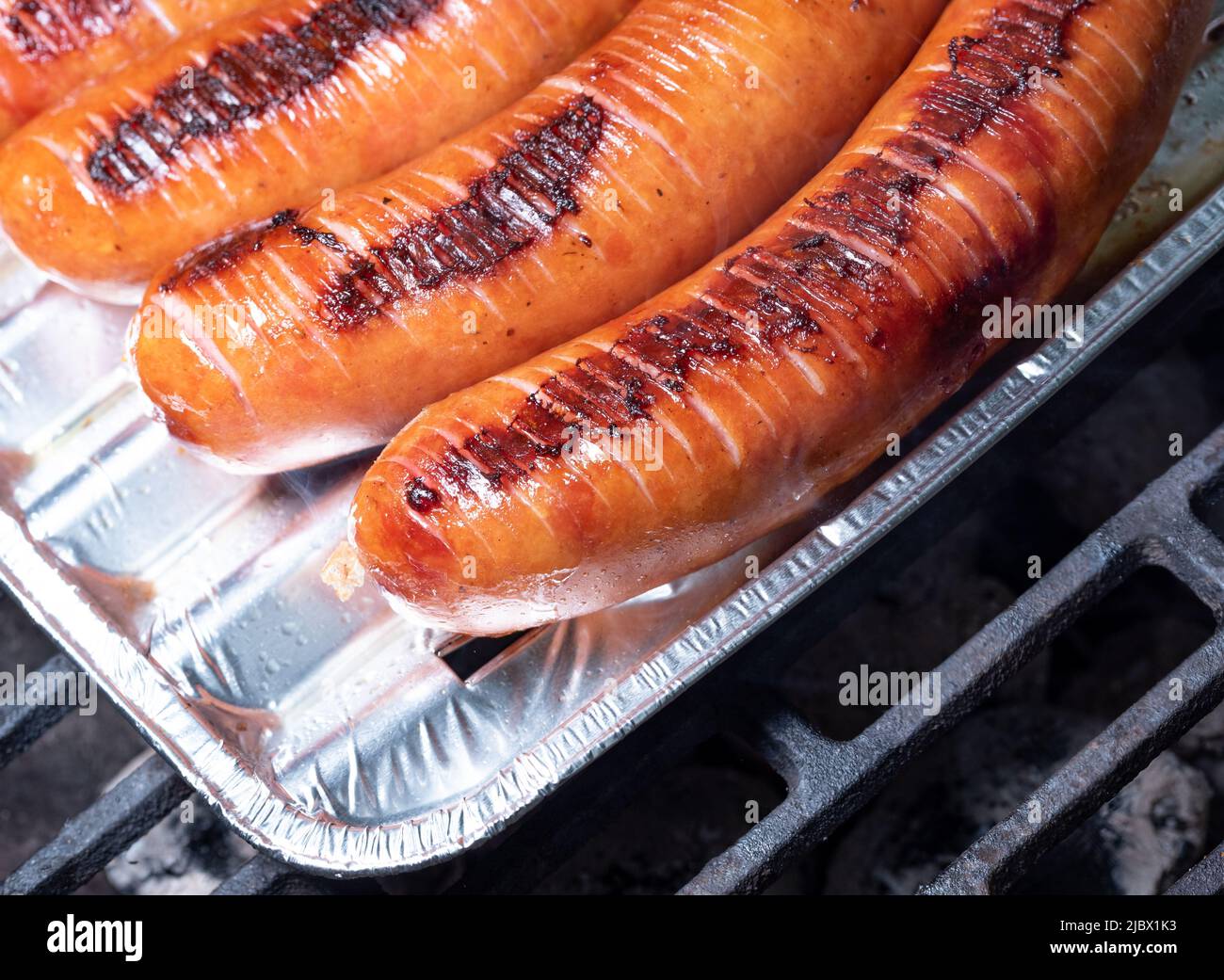 Grilled sausage on an aluminum pad. Barbecue, food preparation, bake