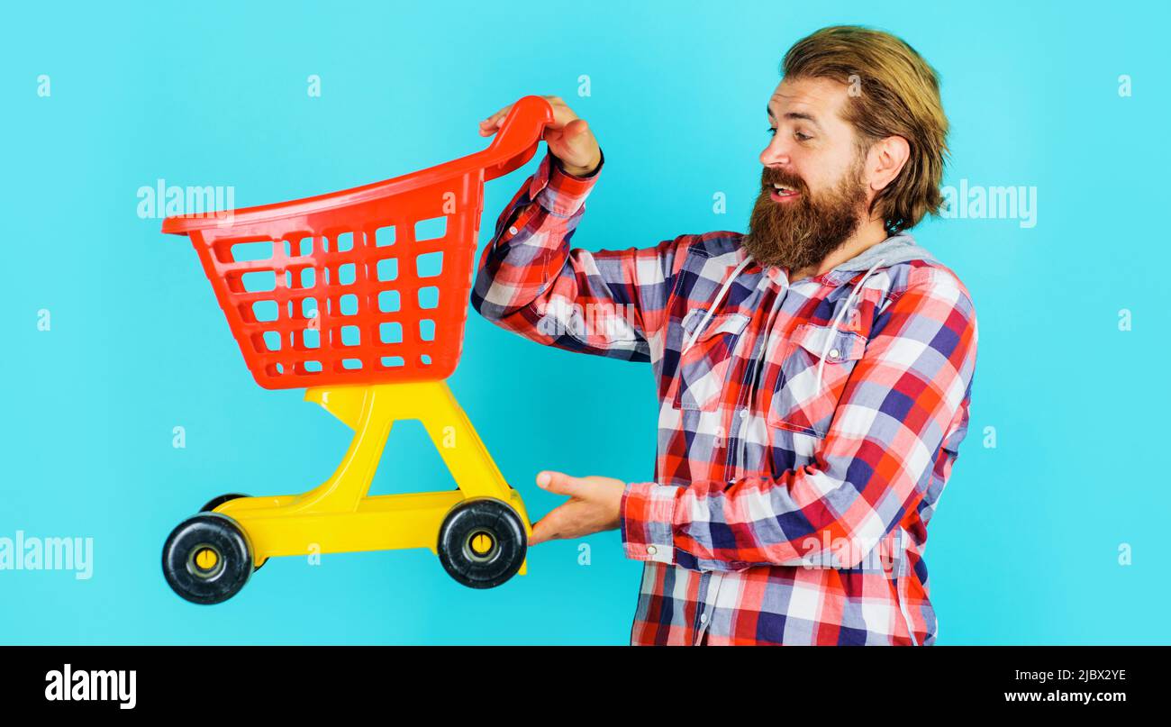 Bearded man with small empty shopping cart or trolley. Grocery store. Sale. Discount. Buying. Stock Photo