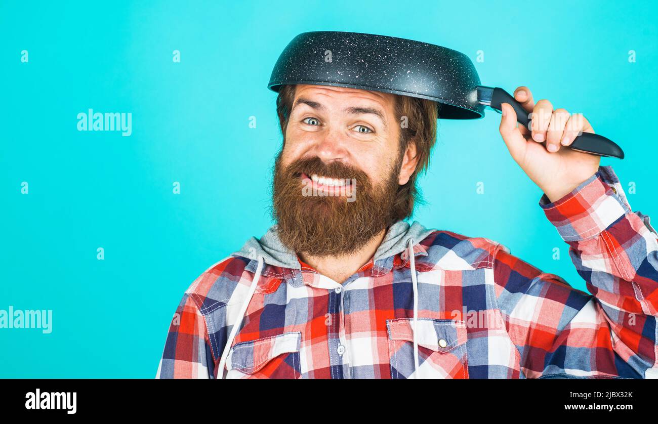 Kitchenware. Bearded man with frying pan on head. Cooking utensils