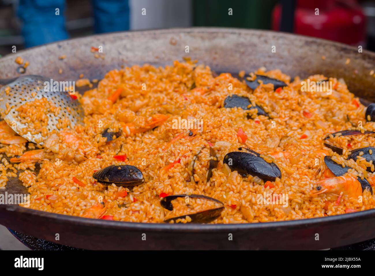 Orange paella with shrimp, mussel, rice, spice, saffron in huge paella
