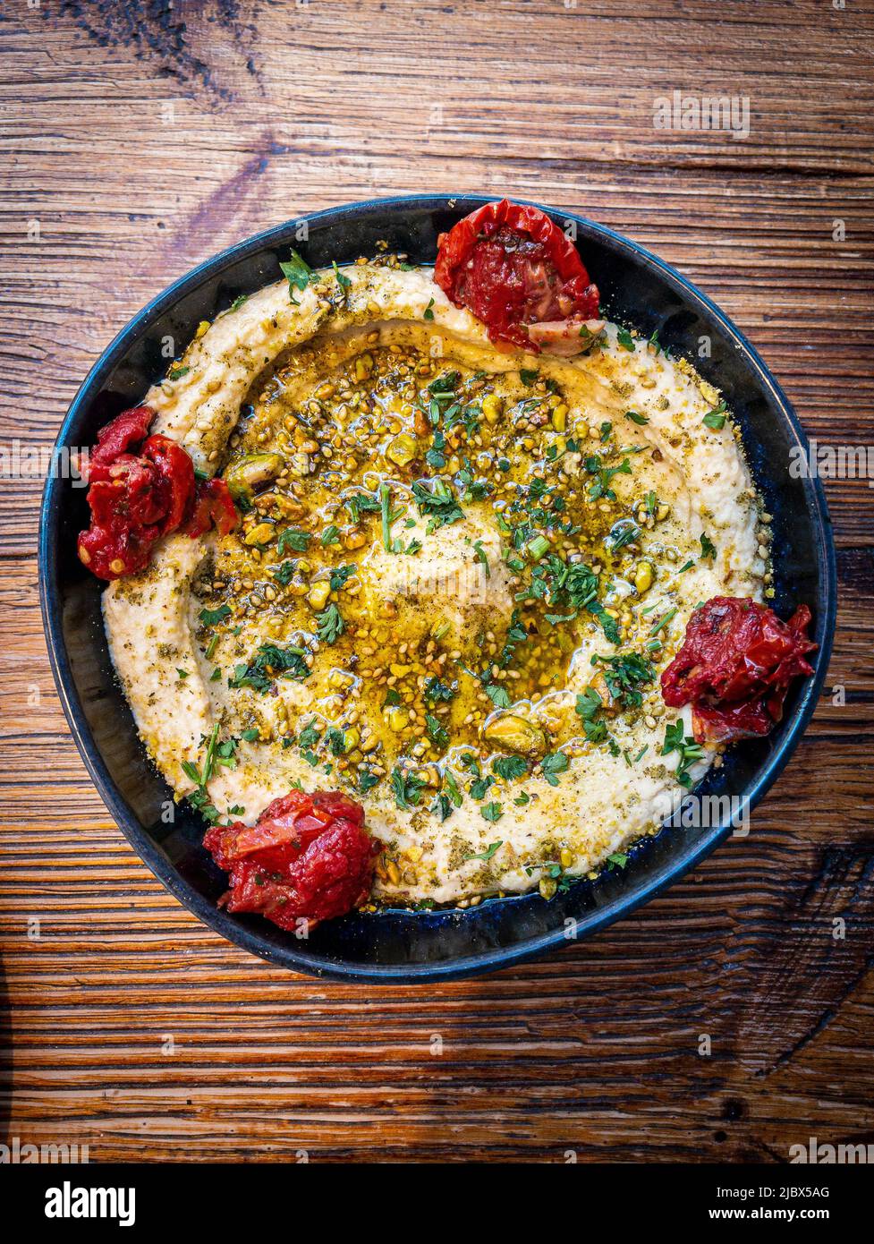 https://c8.alamy.com/comp/2JBX5AG/hummus-topped-with-sesame-seeds-olive-oil-and-chopped-cilantro-2JBX5AG.jpg