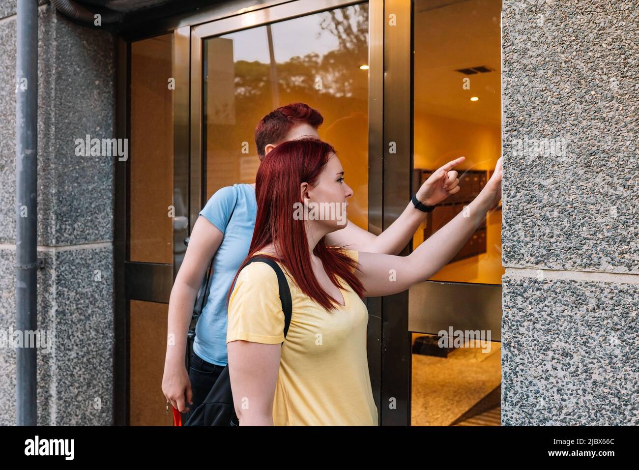Side image of two young friends, ringing the doorbell of their friend's ...