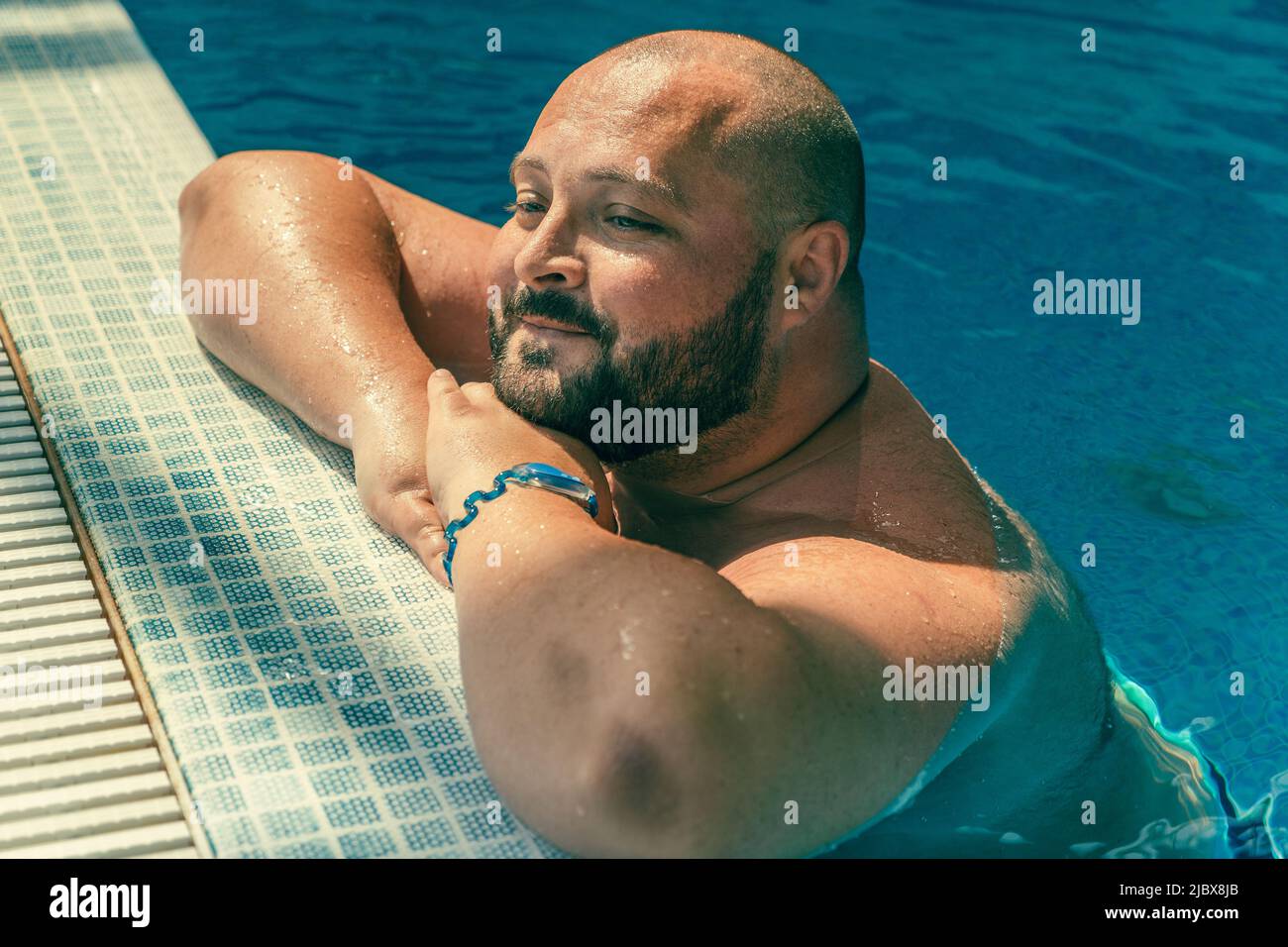 Portrait of plus size big happy smiling man relaxing in swimming pool. Stock Photo