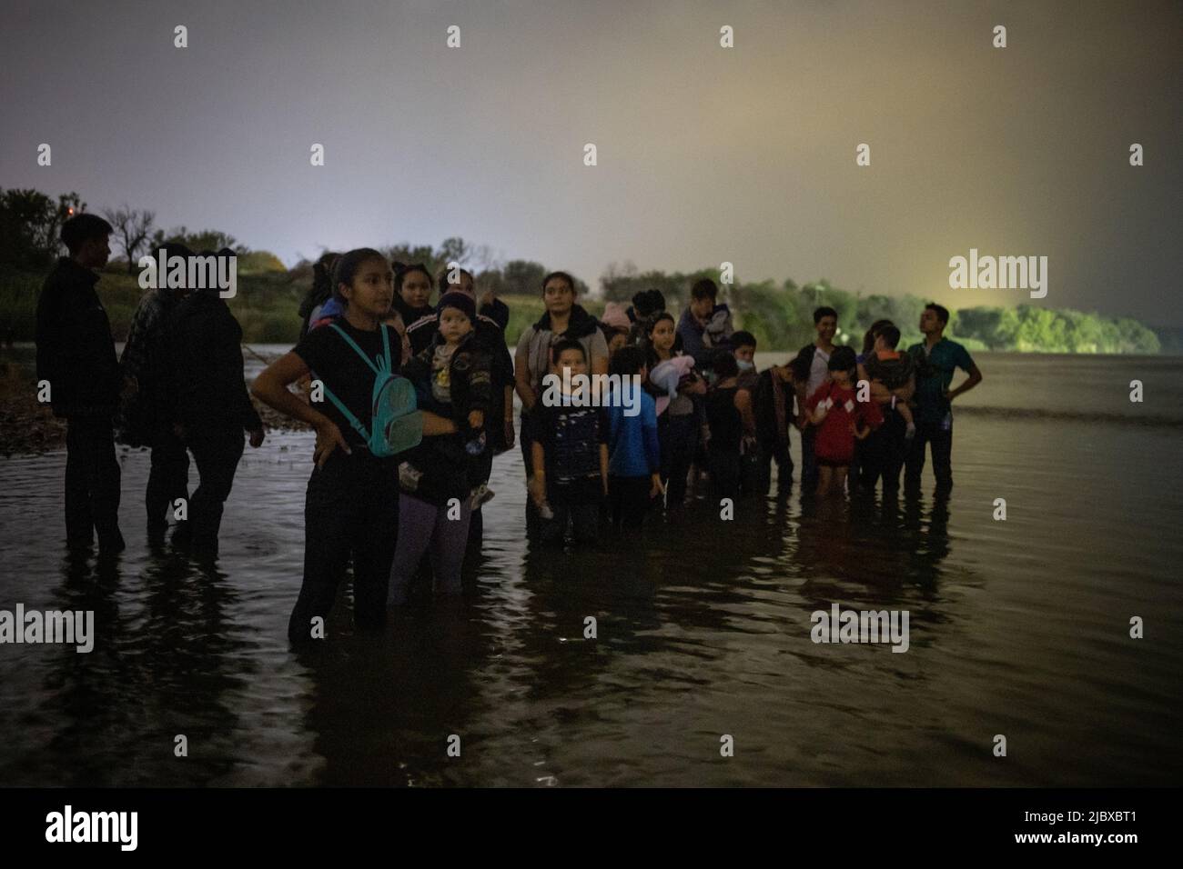 Asylum seeking migrants from Central and South America stand on a sandbar as they await to be smuggled across the Rio Grande river into the United States from Mexico in Roma, Texas, June 8, 2022.  REUTERS/Adrees Latif Stock Photo