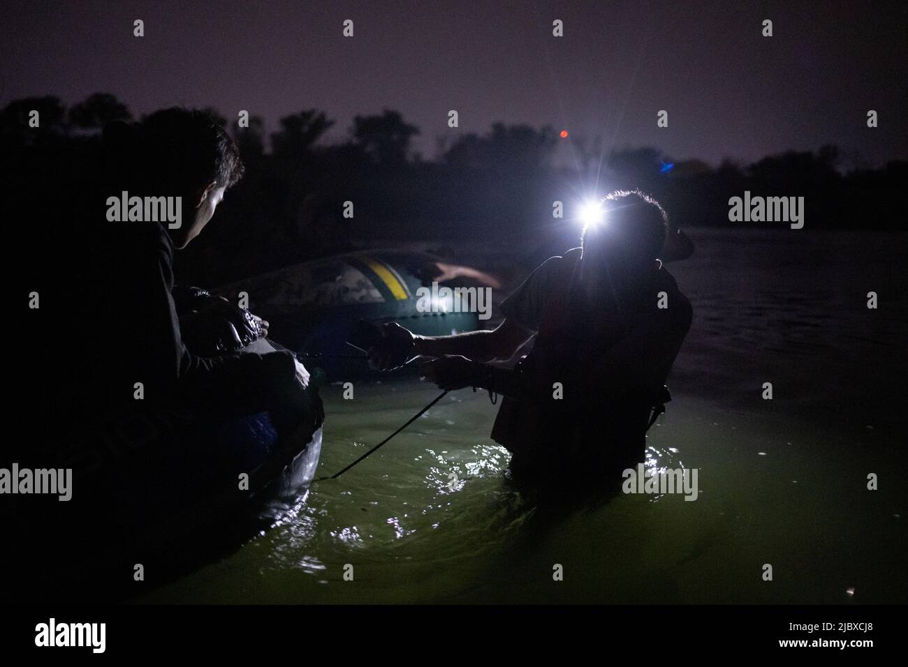 A smuggler pulls a raft with asylum seeking migrants from Central and South America as they cross the Rio Grande river into the United States from Mexico in Roma, Texas, June 8, 2022.  REUTERS/Adrees Latif Stock Photo