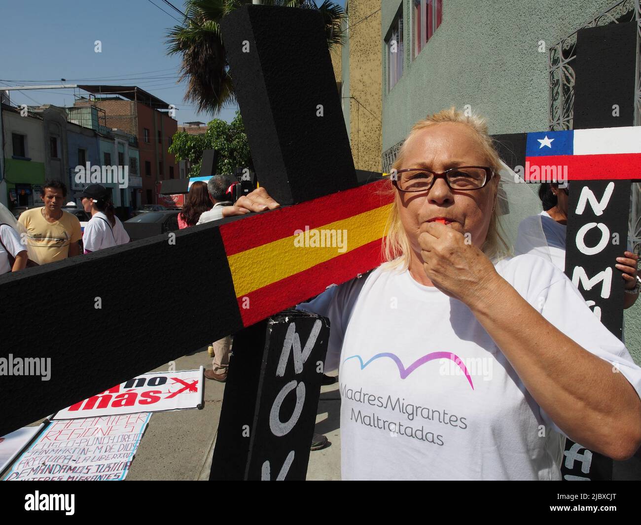 A woman carries a black cross marked with a Spanish flag, as part of a group of women, inmigrant mothers, with children born in Peru, who demonstrated in front of the building of the National Migration Superintendence, requesting them to be granted Peruvian residency and allow them to stay in the country. Stock Photo