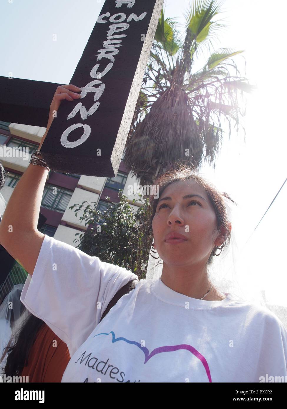 A woman carries a black cross marked with a Spanish flag, as part of a group of women, inmigrant mothers, with children born in Peru, who demonstrated in front of the building of the National Migration Superintendence, requesting them to be granted Peruvian residency and allow them to stay in the country. Stock Photo