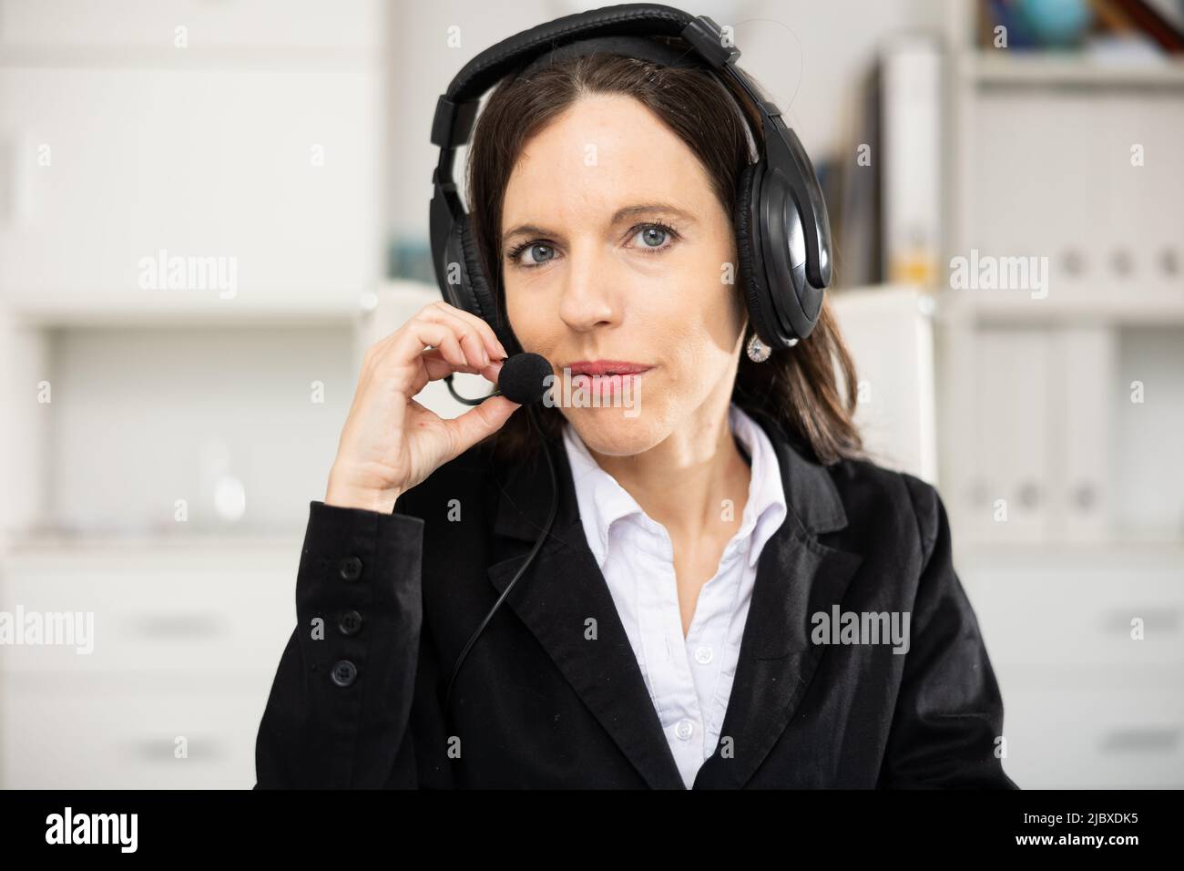 Portrait of woman office worker wearing headphones with microphone Stock Photo